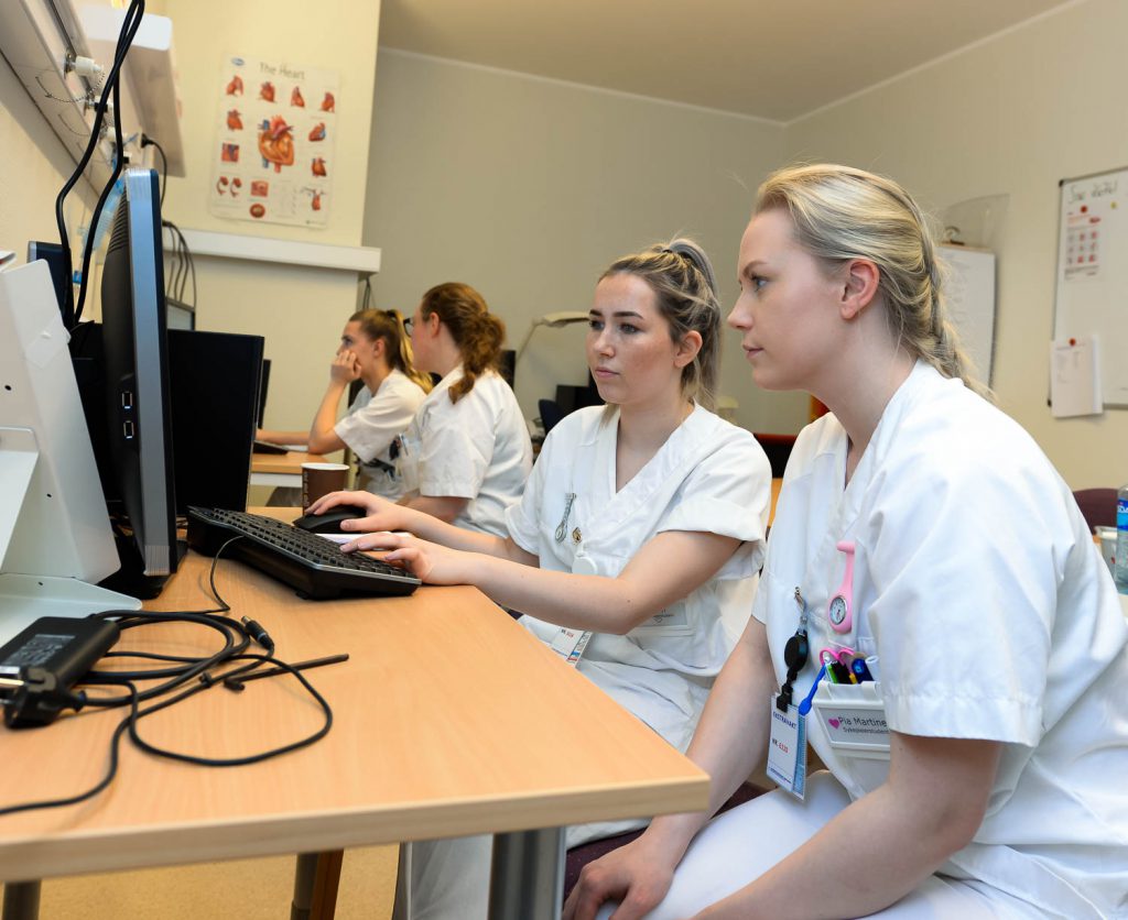 En gruppe kvinner i hvite skjorter som jobber foran datamaskiner