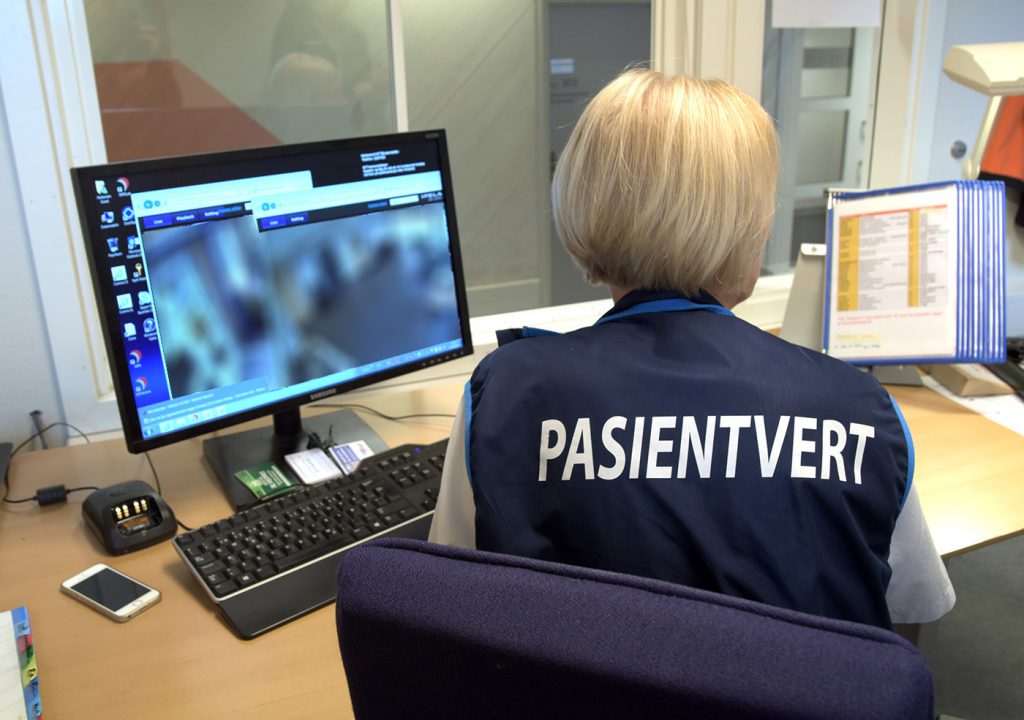 En person som sitter ved et skrivebord med en datamaskin og en telefon