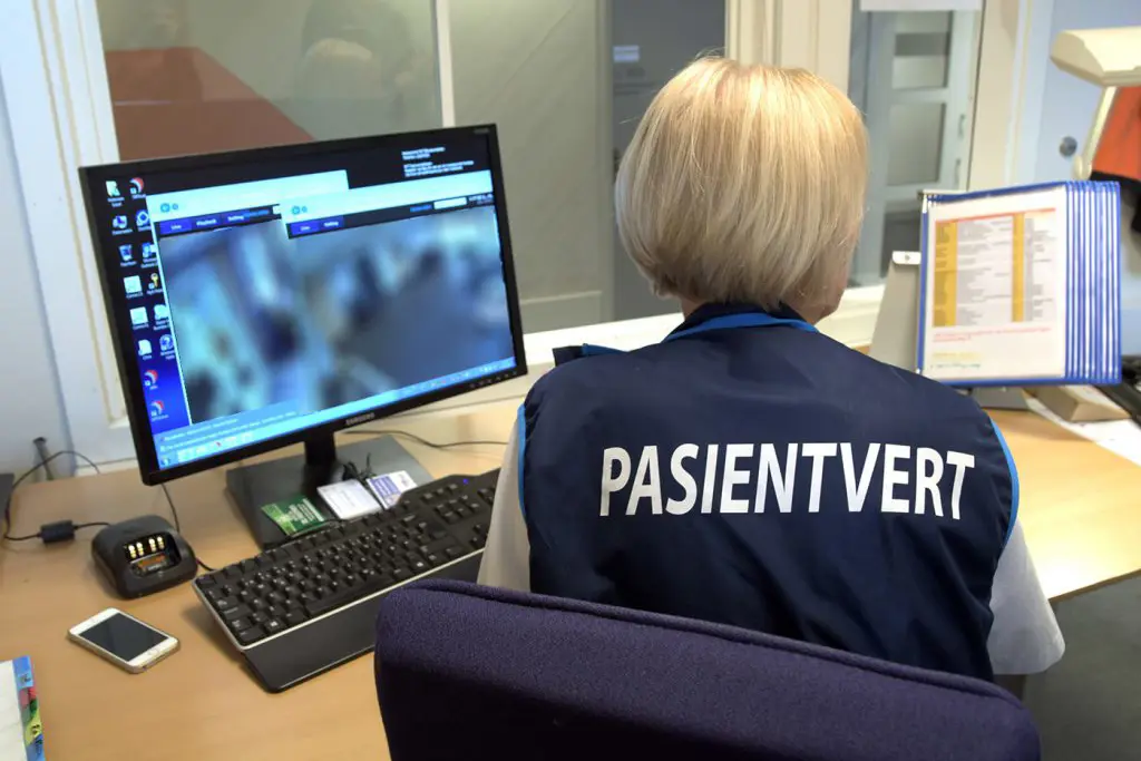 En person som sitter ved et skrivebord med en datamaskin og en telefon