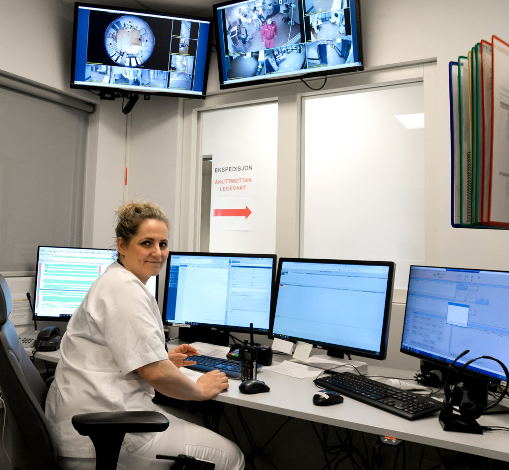 En mann som sitter ved et skrivebord med flere skjermer