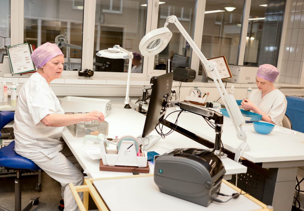 Et par kvinner i et rom med maskiner og et bord