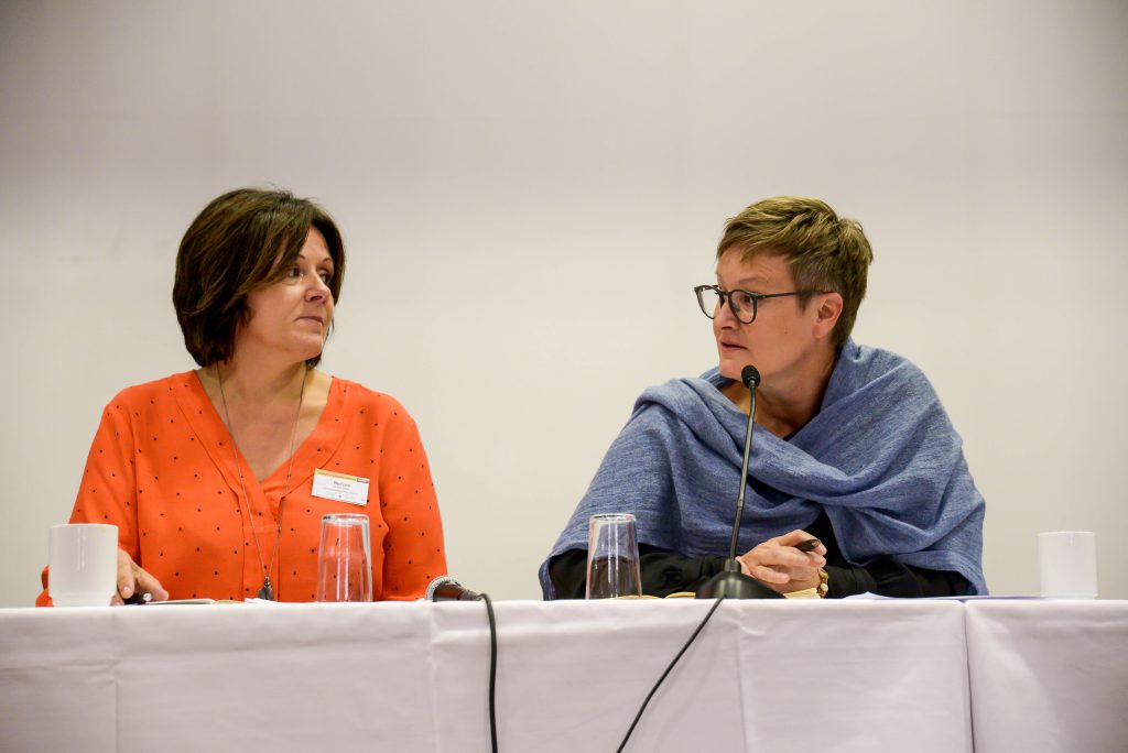 En mann og en kvinne sitter ved et bord med mikrofoner