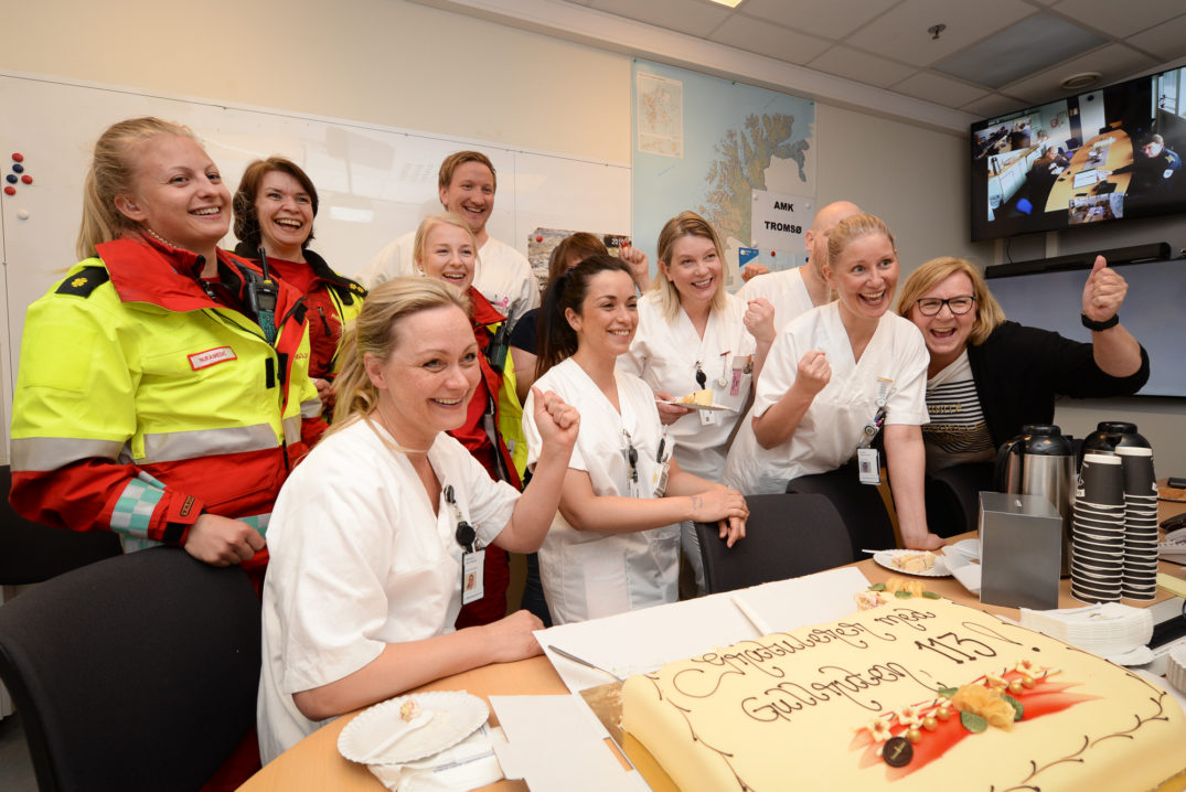 En gruppe mennesker som står rundt en kake