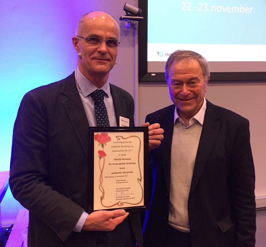 En mann som holder et sertifikat ved siden av en annen mann