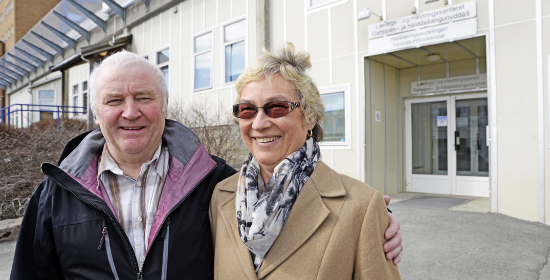 En mann og en kvinne poserer for et bilde utenfor en bygning