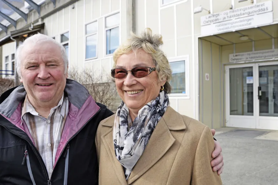 En mann og en kvinne poserer for et bilde utenfor en bygning