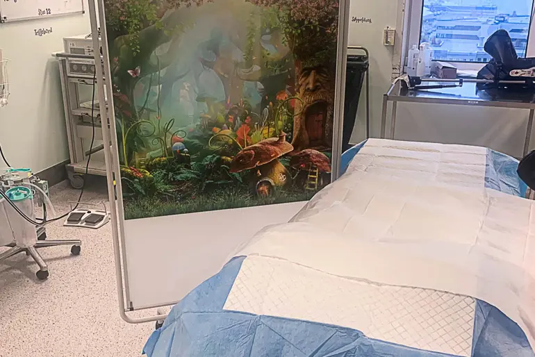Operasjonssal med seng og en fargerik skillevegg