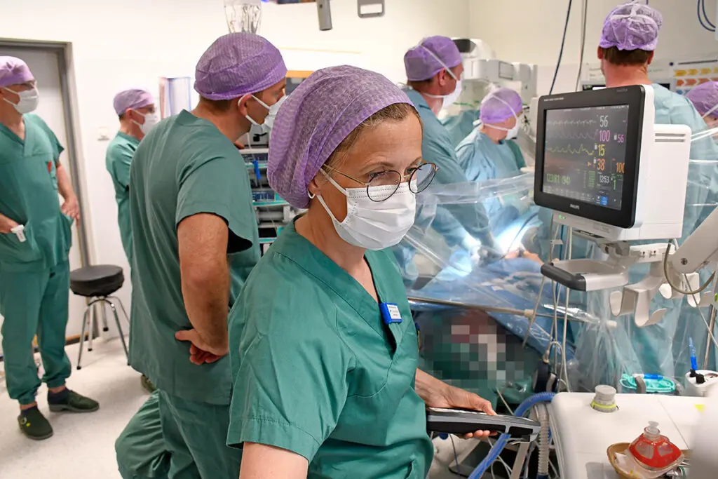 Mye folk kledd i grønt og med munnbind i en operasjonssal.