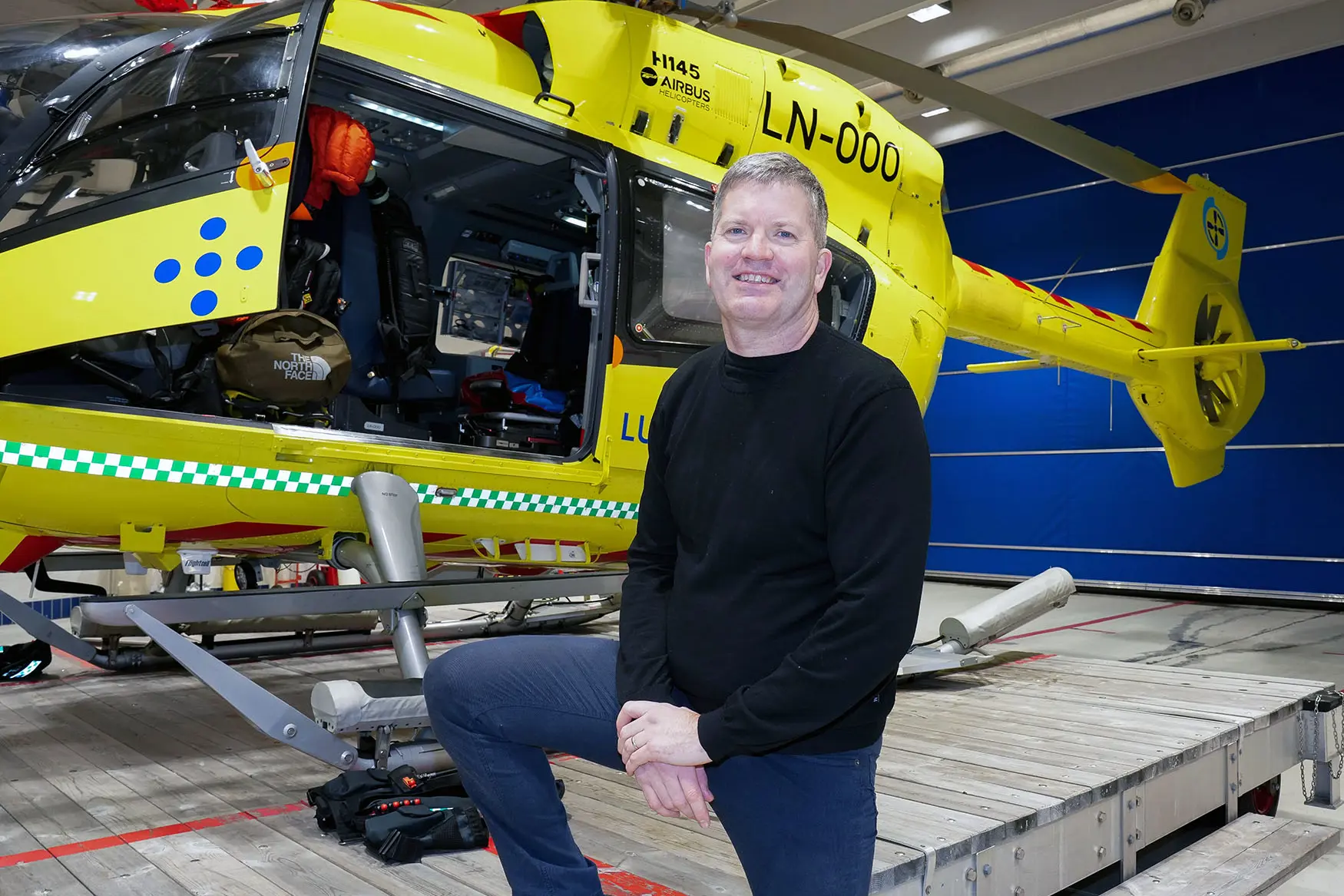 En person som står foran et gult helikopter