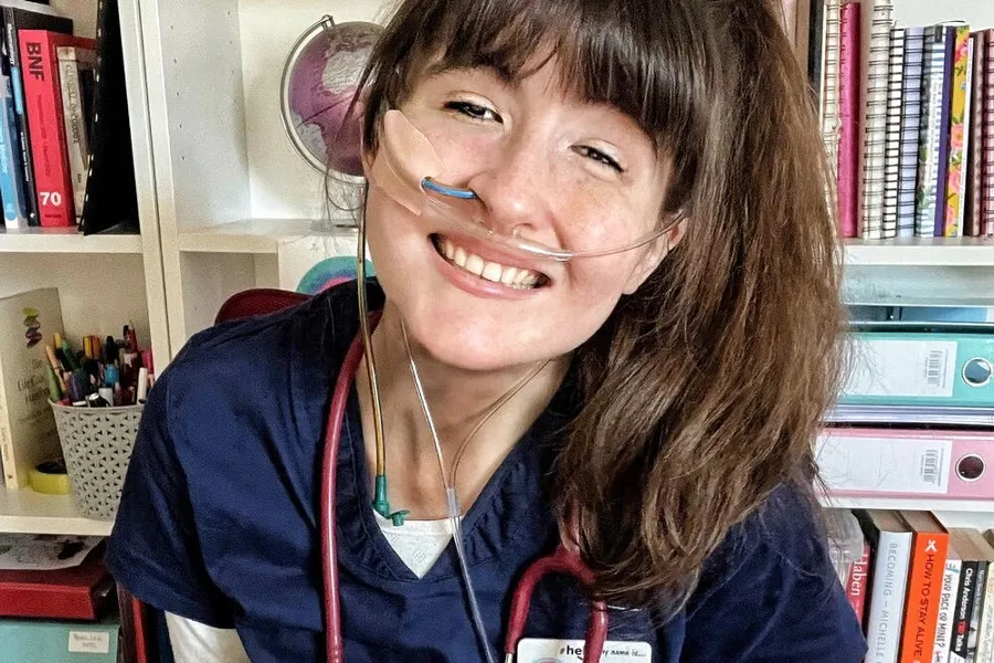 Nærbilde av kvinne med blå trøye og stetoskop hengende rundt halsen.