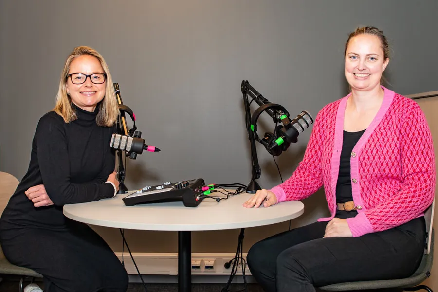 To kvinner som sitter ved et bord med mikrofoner