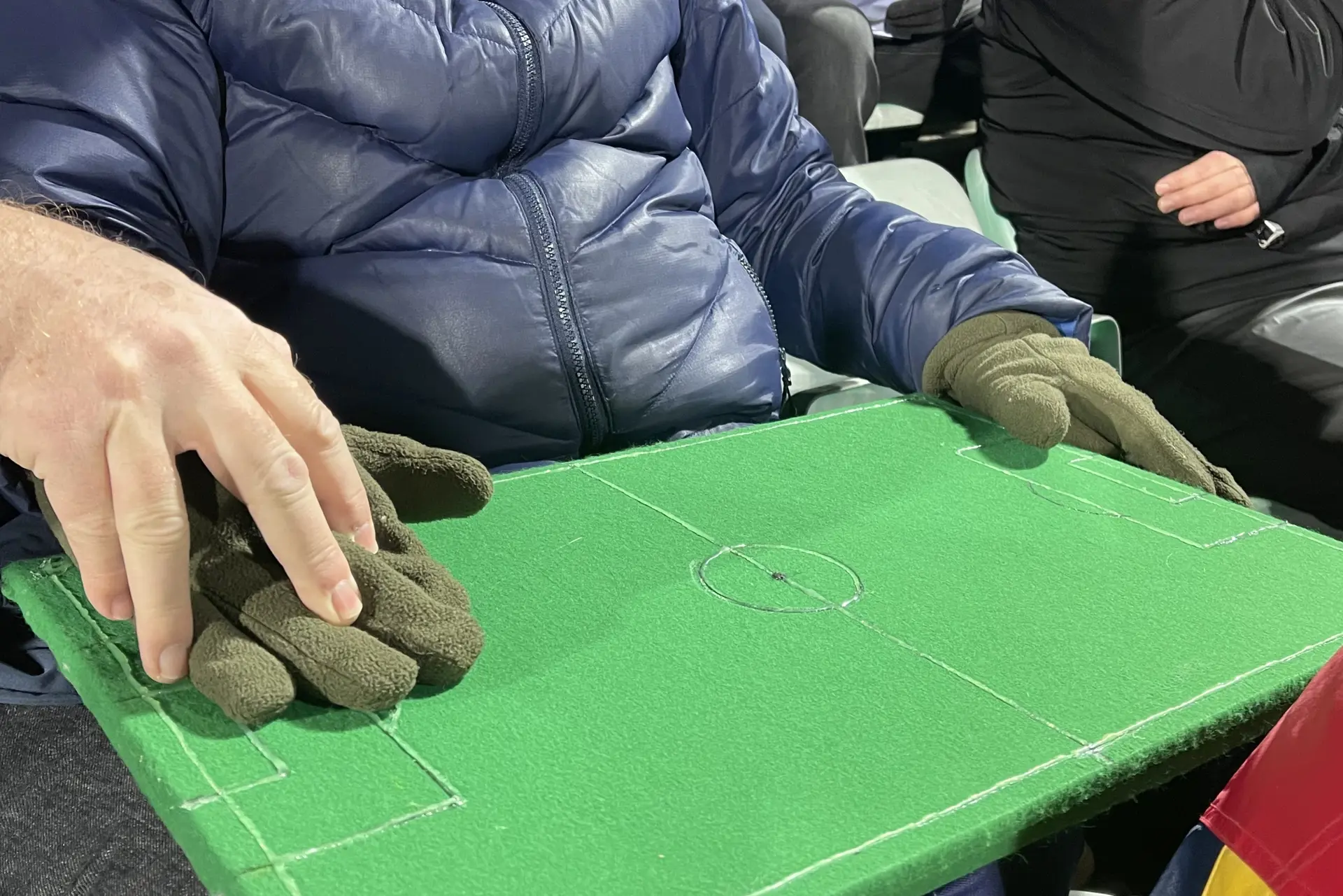 En person som holder modell av en fotballbane på fanget