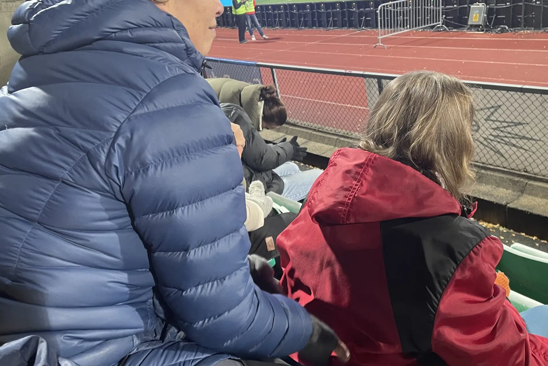 Et par personer som sitter på en benk og ser på en fotballbane