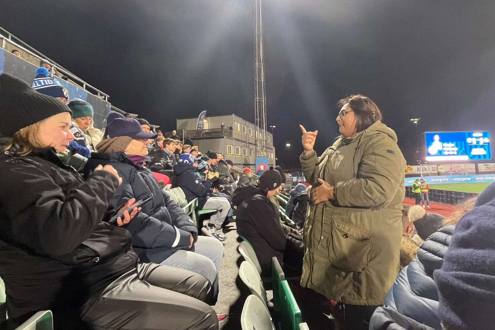 En gruppe mennesker som sitter på en benk og en tolk som står foran dem