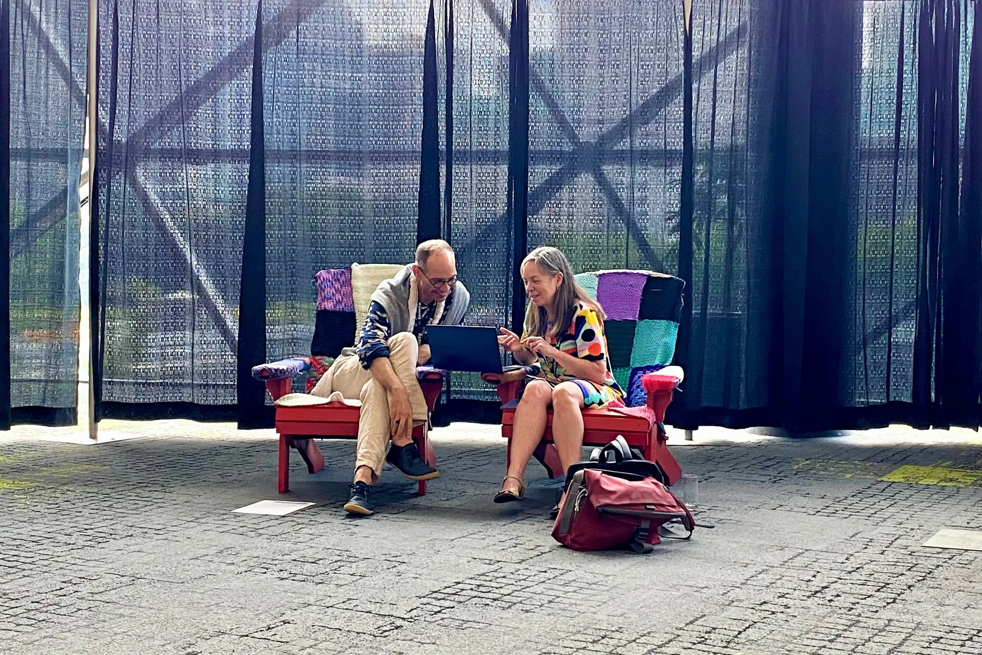 En mann og en kvinne som sitter på en benk og surfer på en laptop