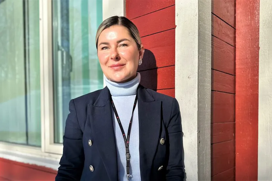 Portrettbilde av kvinne utenfor en rødmalt vegg