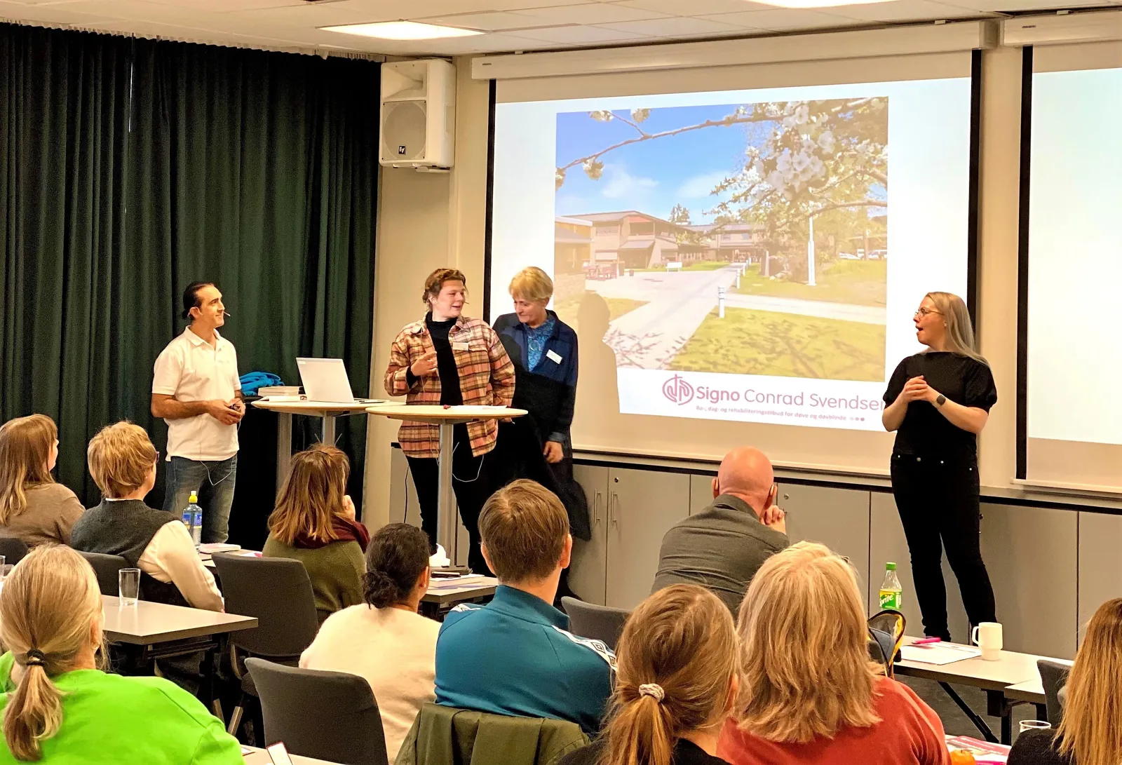 En gruppe mennesker foran en projektorskjerm