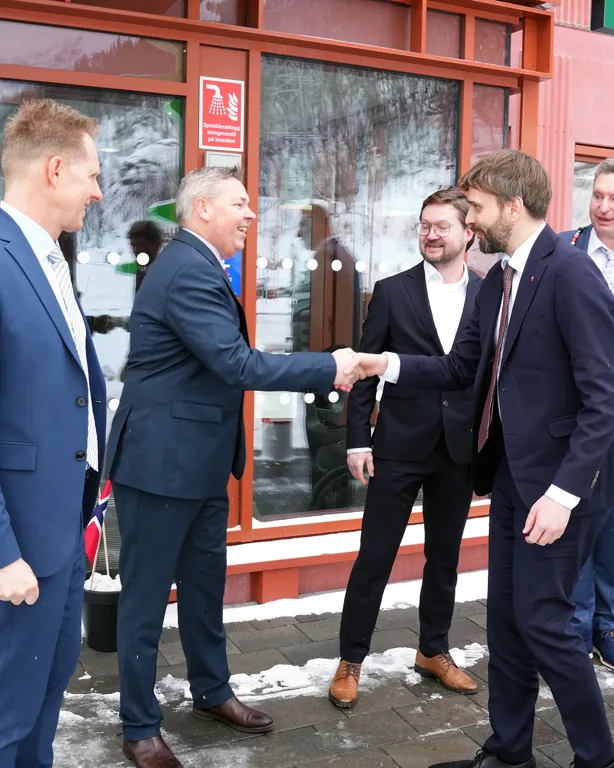 Fire festkledde menn som håndhilser