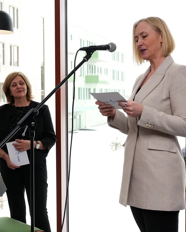 En person som holder en mikrofon og en person i bakgrunnen