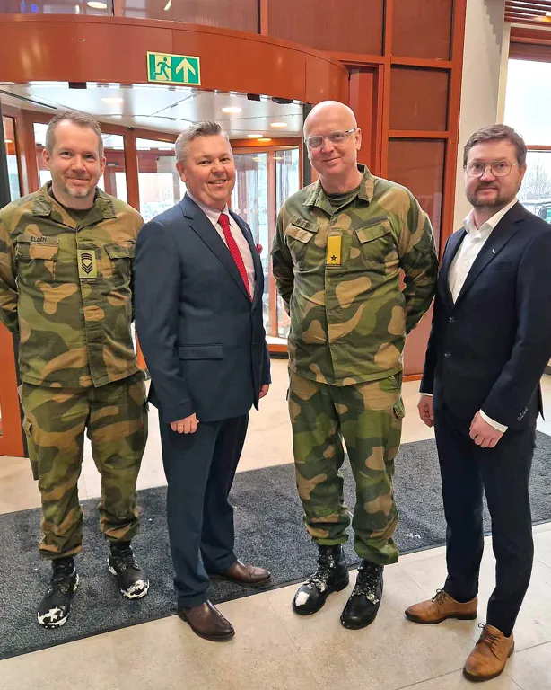 Fire menn som poserer for et bilde ( to i grønne militæruniformer og to i dress)