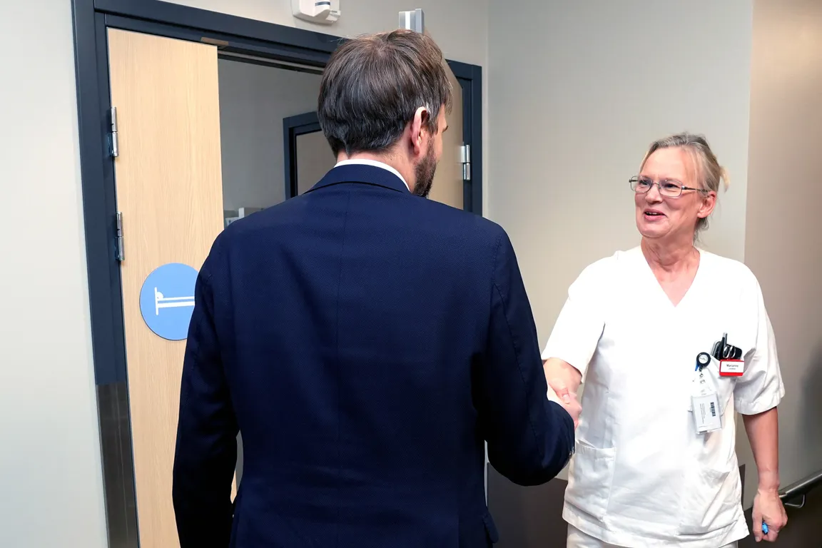 En dresskledd mann og en kvinne i sykehusuniform