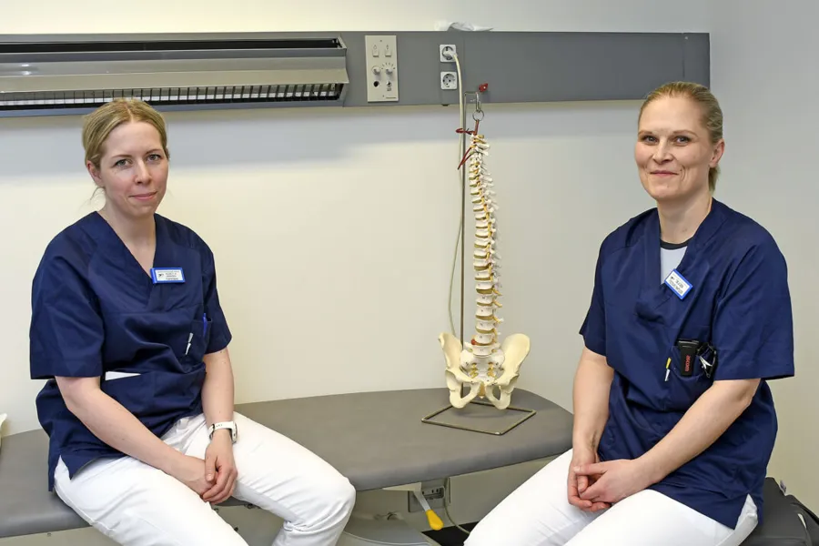 To lyshåra damer i blå arbeids-antrekk som sitter