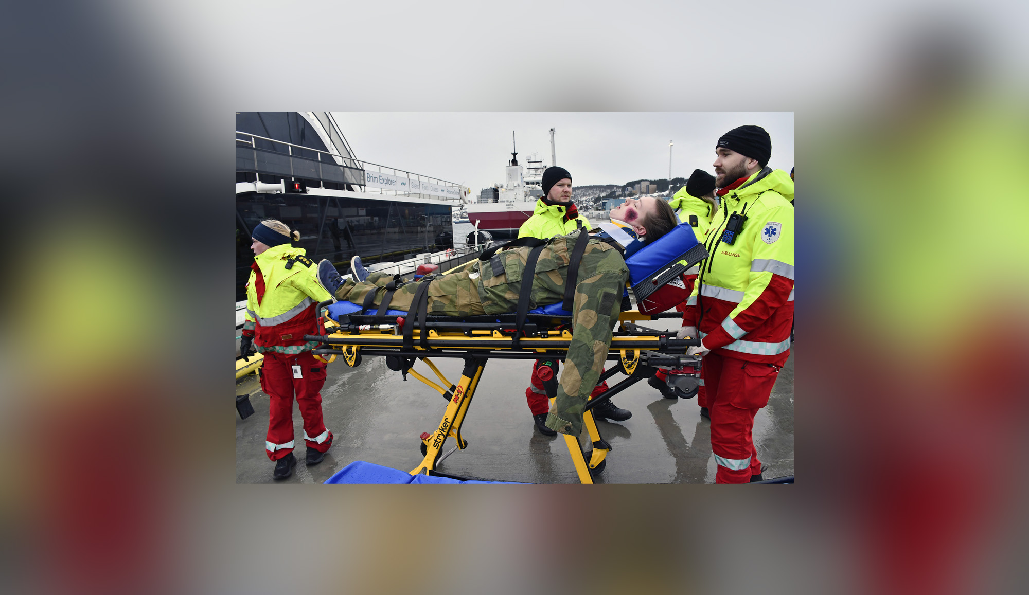 En gruppe mennesker i gule jakker og hatter står ved siden av en båt