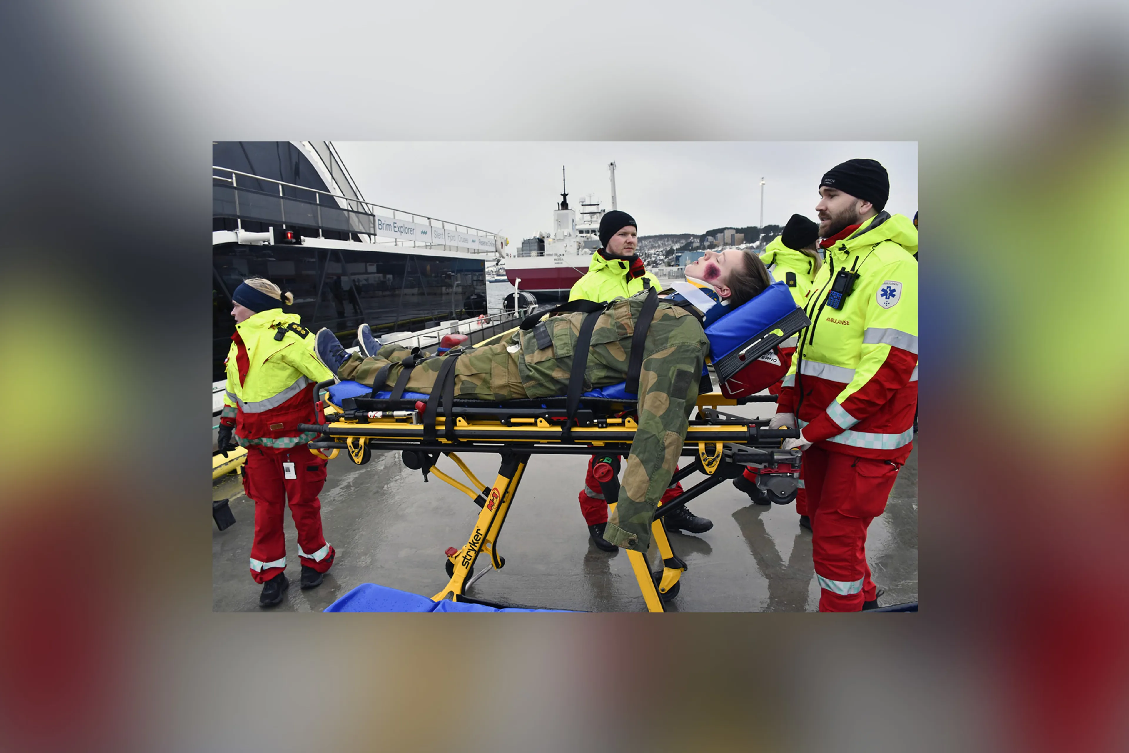 En gruppe mennesker i gule jakker og hatter står ved siden av en båt