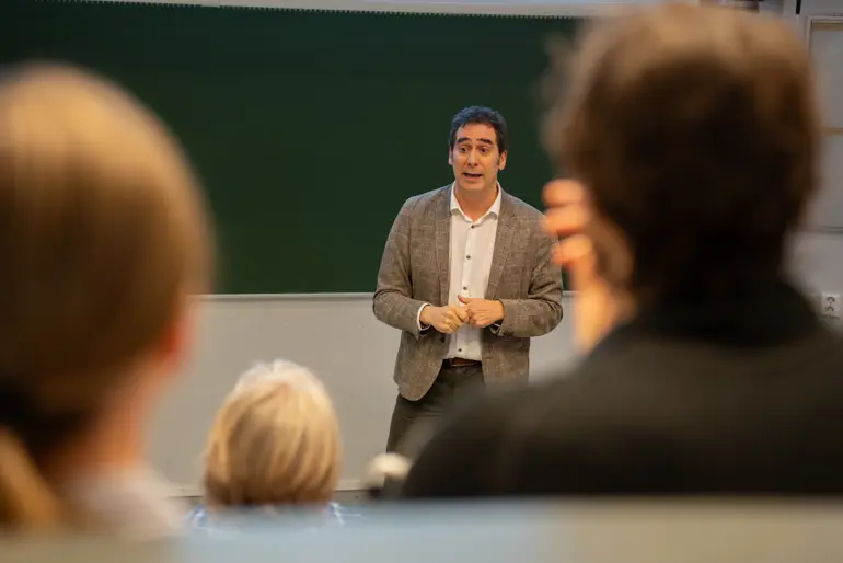 Bildet viser mann som snakker til en forsamling