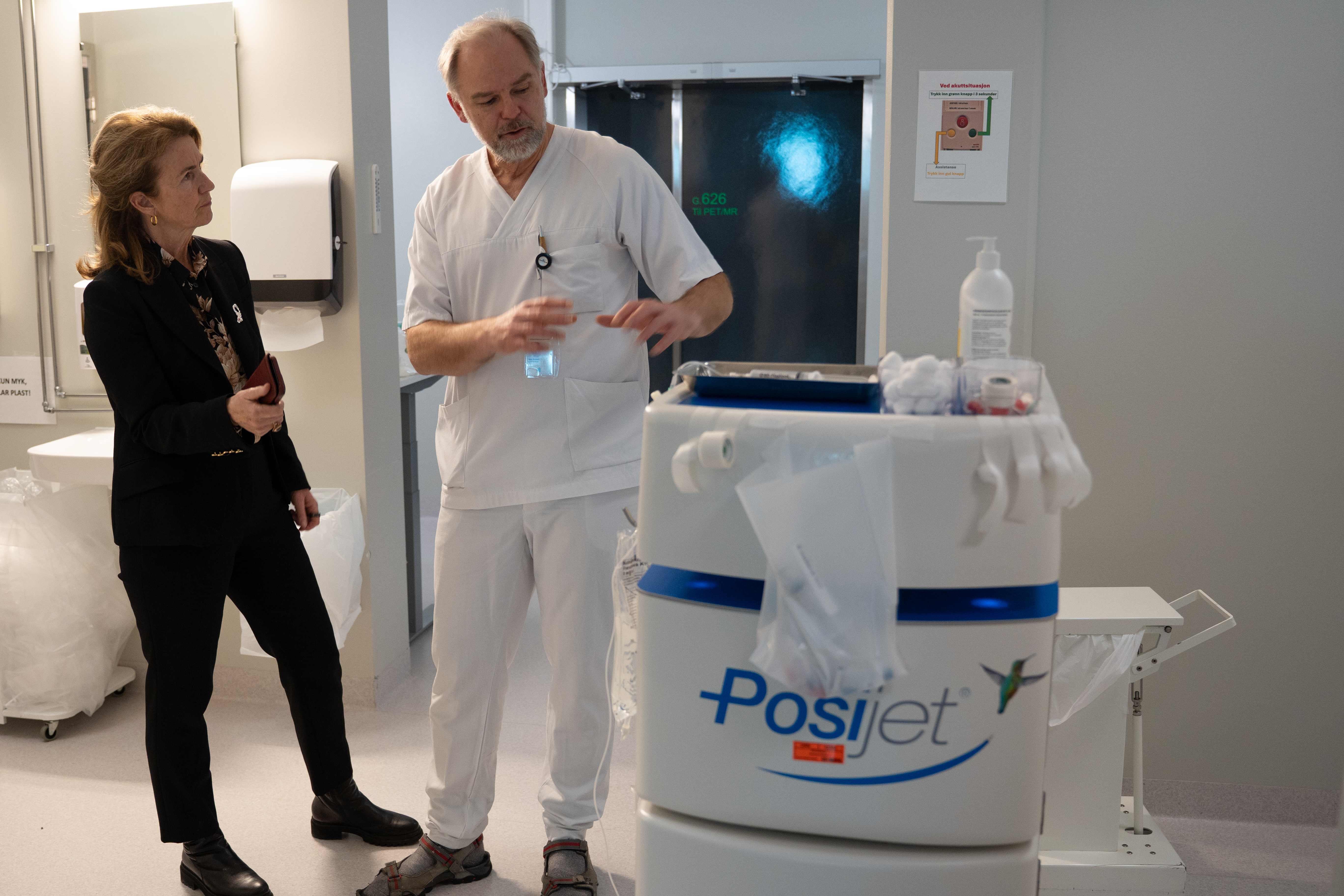 Bildet viser mann som viser en dame en PET-maskin