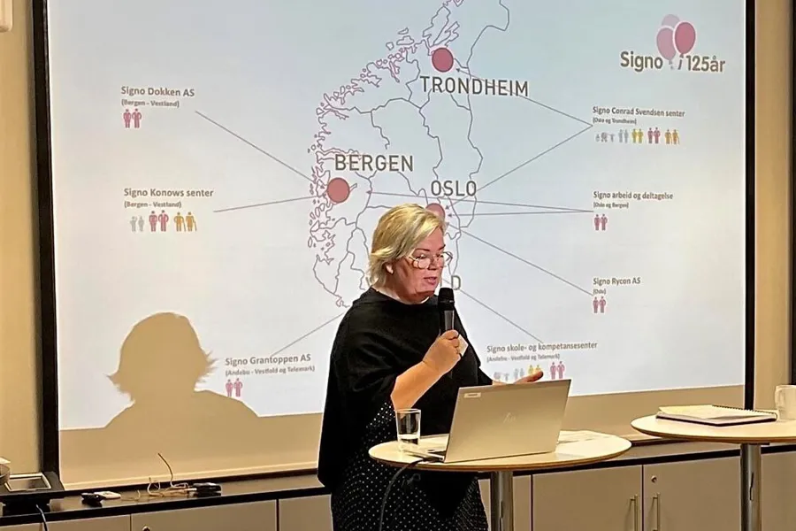 To personer forelese foran to skjermer med powerpoint-slider, samt tegnspråktolk til høyre for dem.