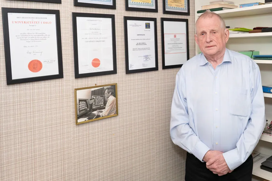 En mann som står foran en vegg med diplomer