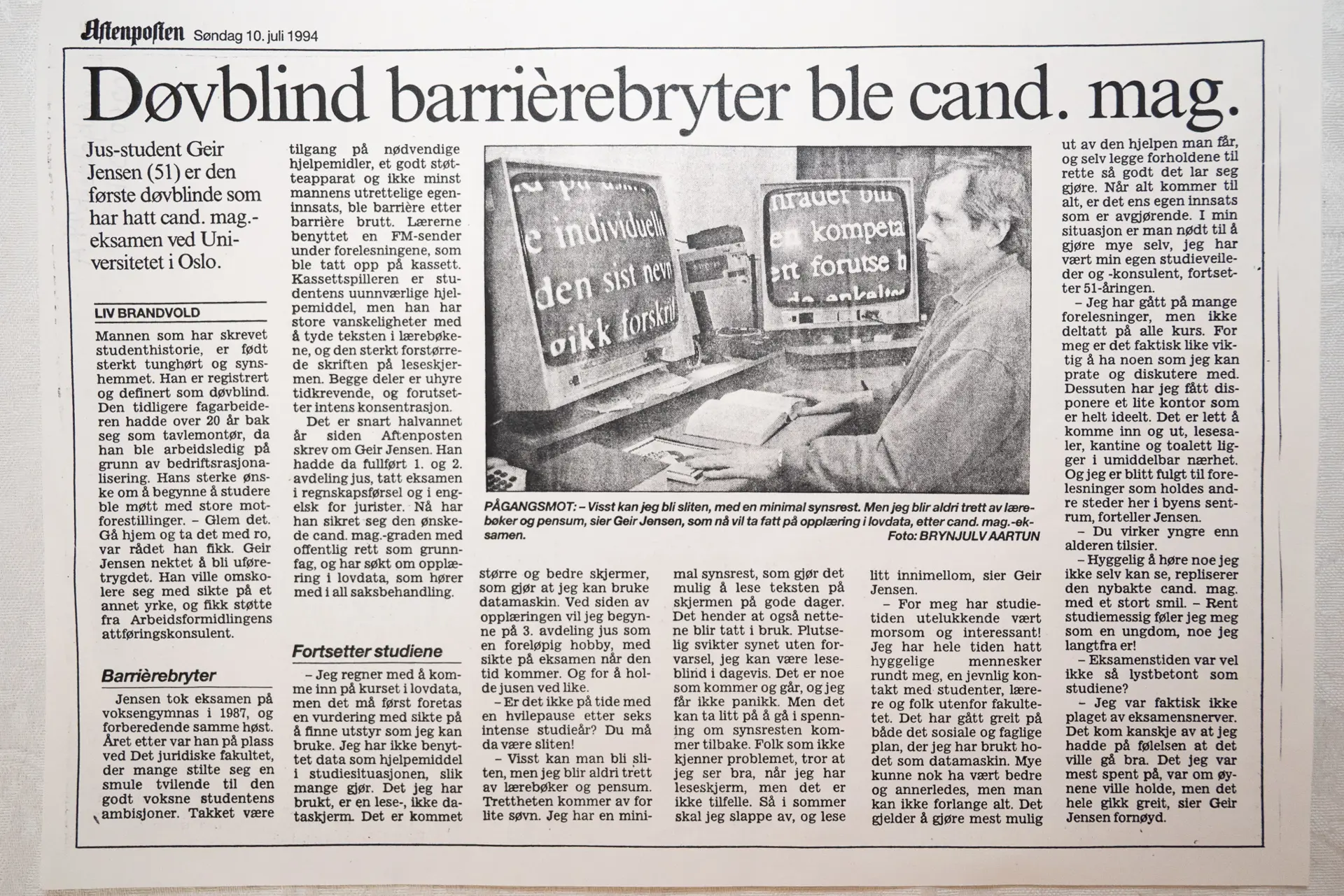 Avis med et bilde av en mann sittende ved to dataskjermer