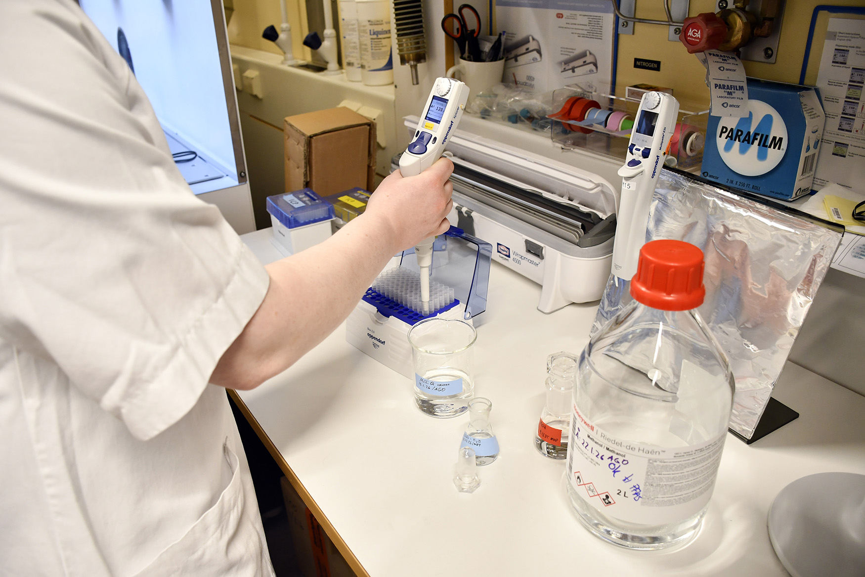 En person i laboratoriefrakk som holder en sprøyte