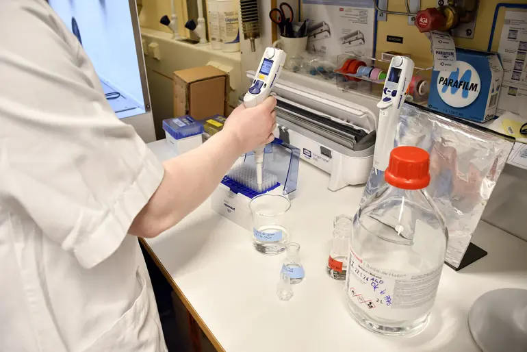 En person i laboratoriefrakk som holder en sprøyte