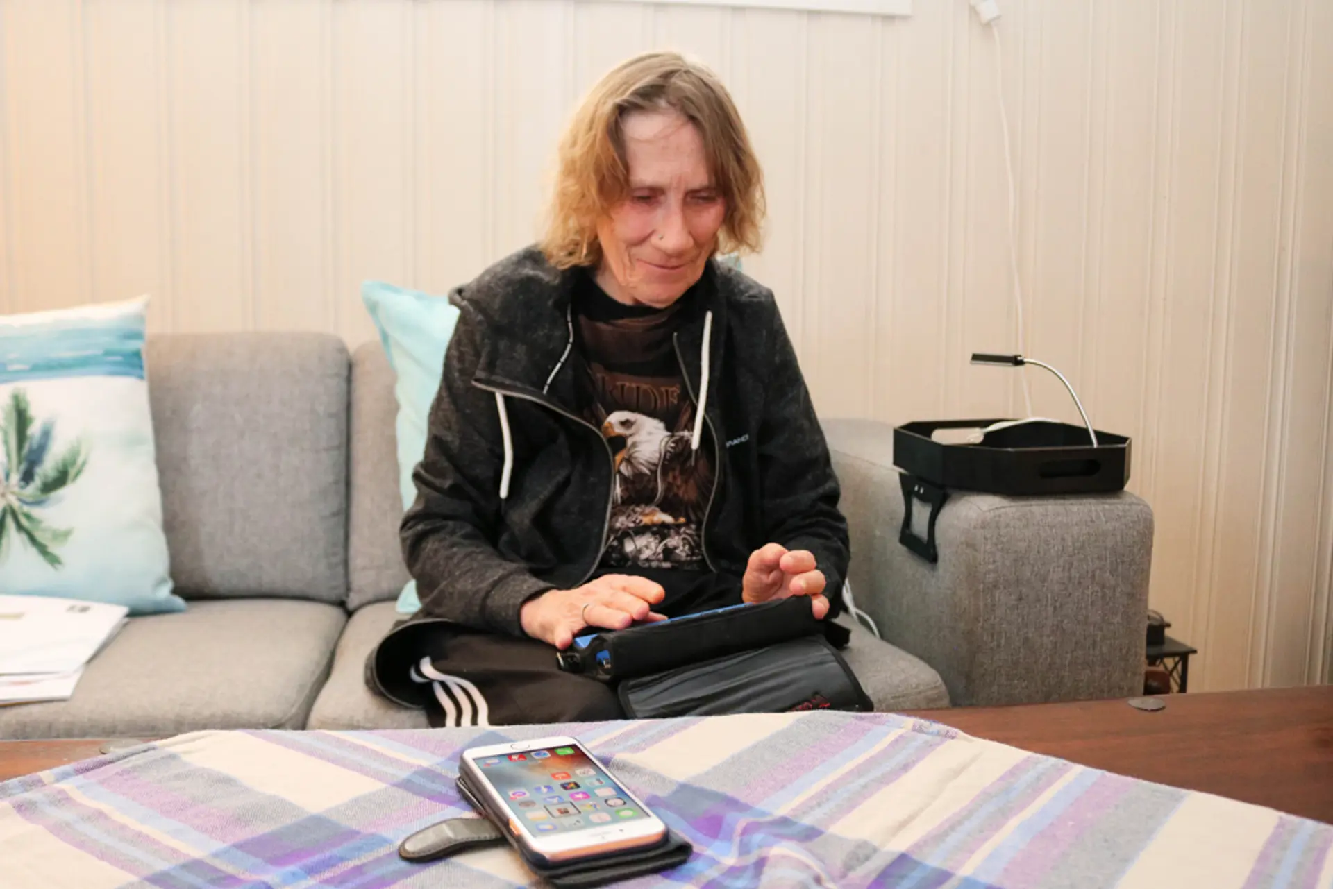 Døvblind dame bruker leselist med punktskrifttastatur til sin mobil.