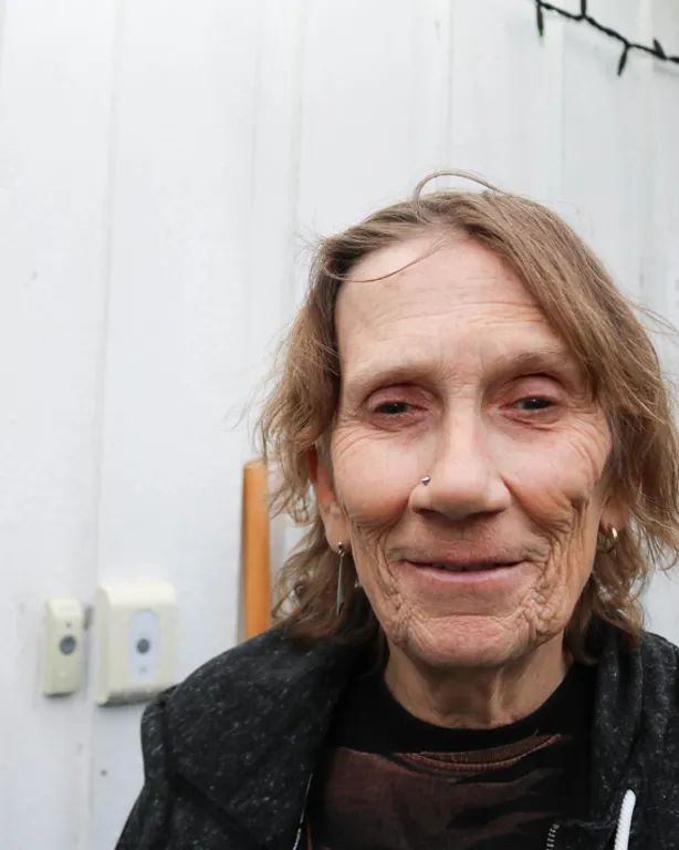 Portrettbilde av døvblind kvinne foran sin egen bolig