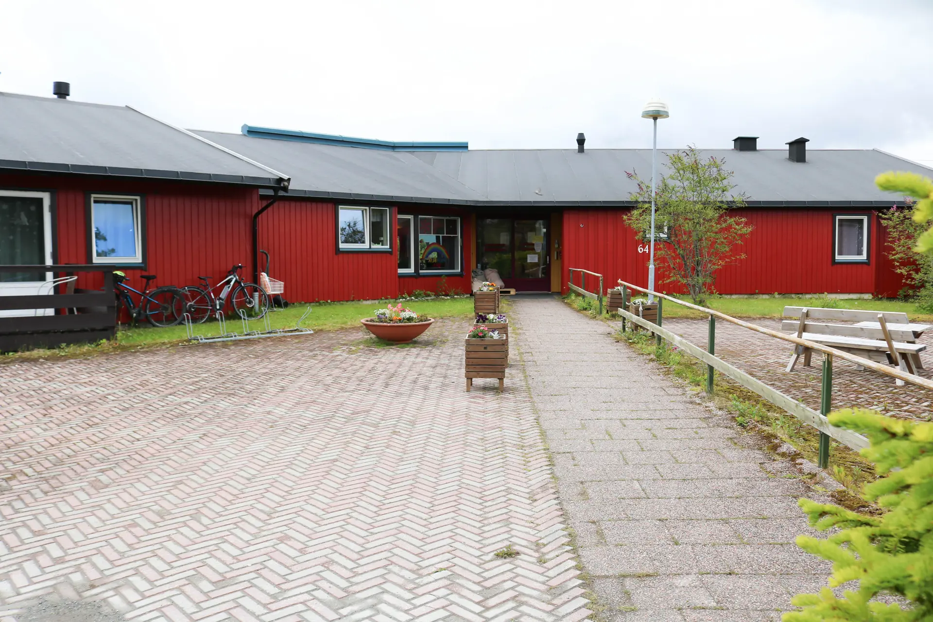 En gangvei i murstein som fører til et rødt trehus