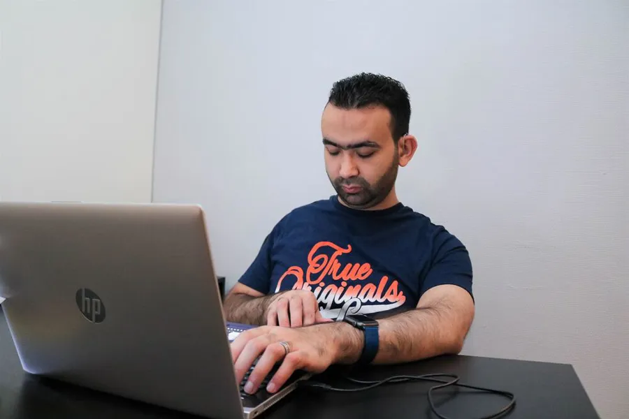 Mann sitter med sin bærbare datamaskin. Han har øynes sine igjen og hendene på tastaturet