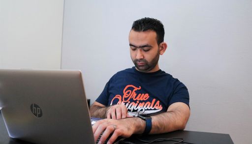 Mann sitter med sin bærbare datamaskin. Han har øynes sine igjen og hendene på tastaturet