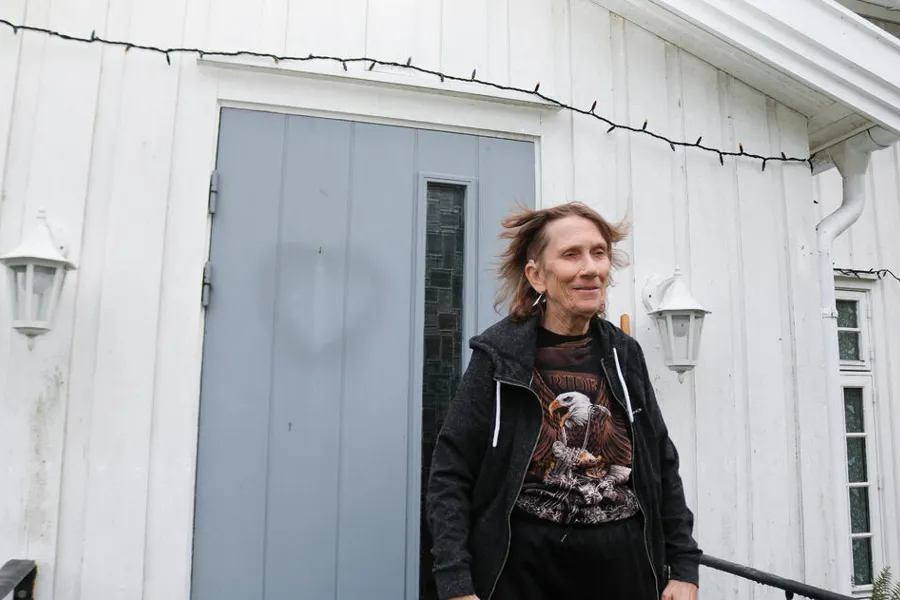 Kvinne som står foran et hvitt hus