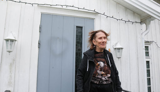 Kvinne som står foran et hvitt hus