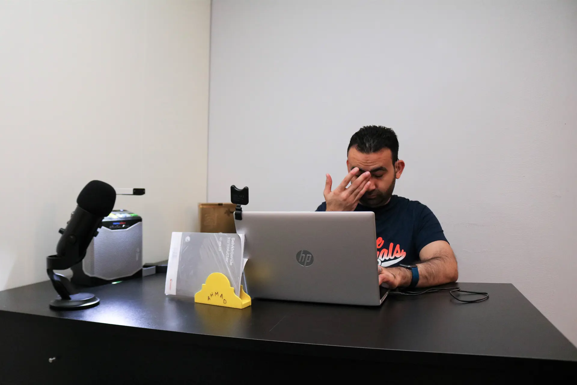 Mann sitter på sin kontorplass og jobber med data. Han holder den ene handa si opp mot ansiktet.