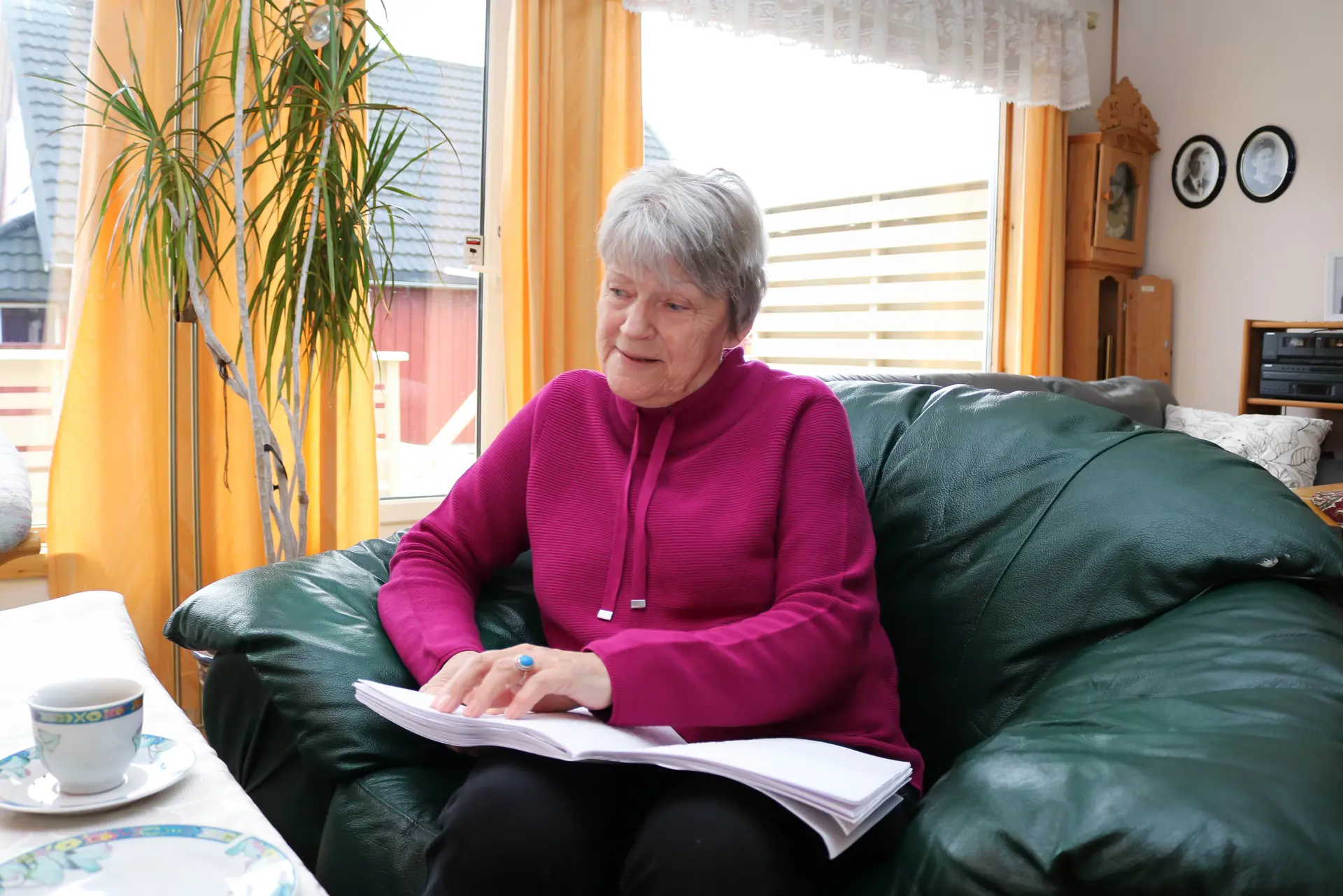 En kvinne som sitter på en sofa og leser en bok