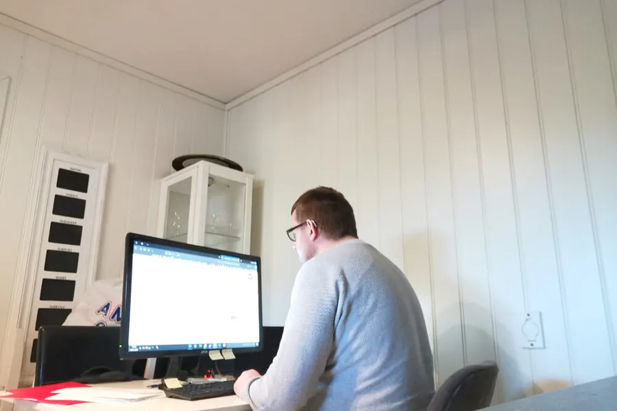 En mann som sitter ved et skrivebord med en datamaskin