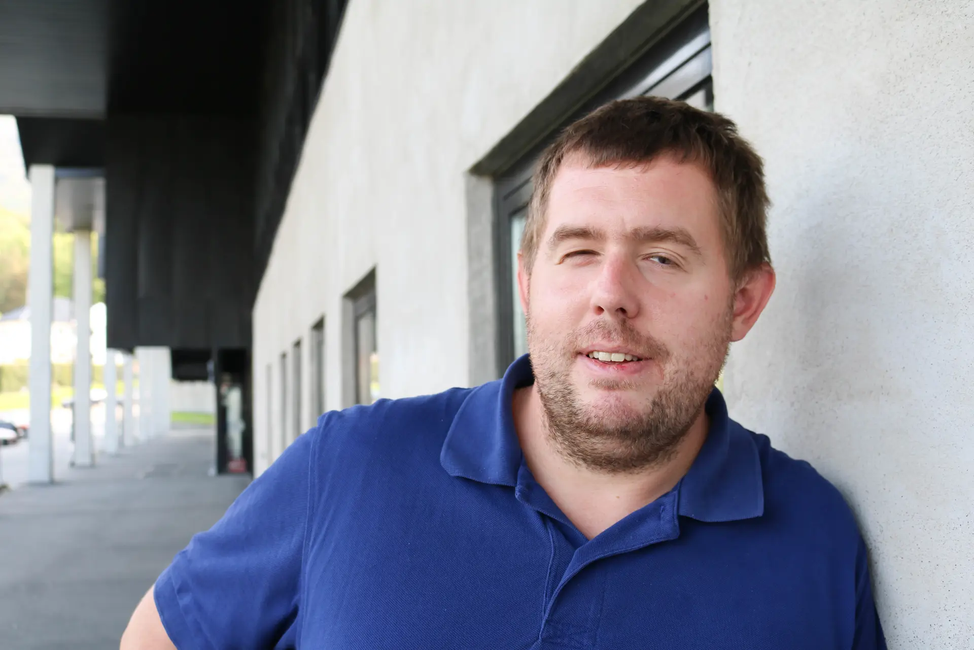 Portrettbilde av mann med mørkeblå pique, grå bakgrunn