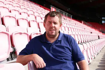 En mann som sitter på en rød tribunestol