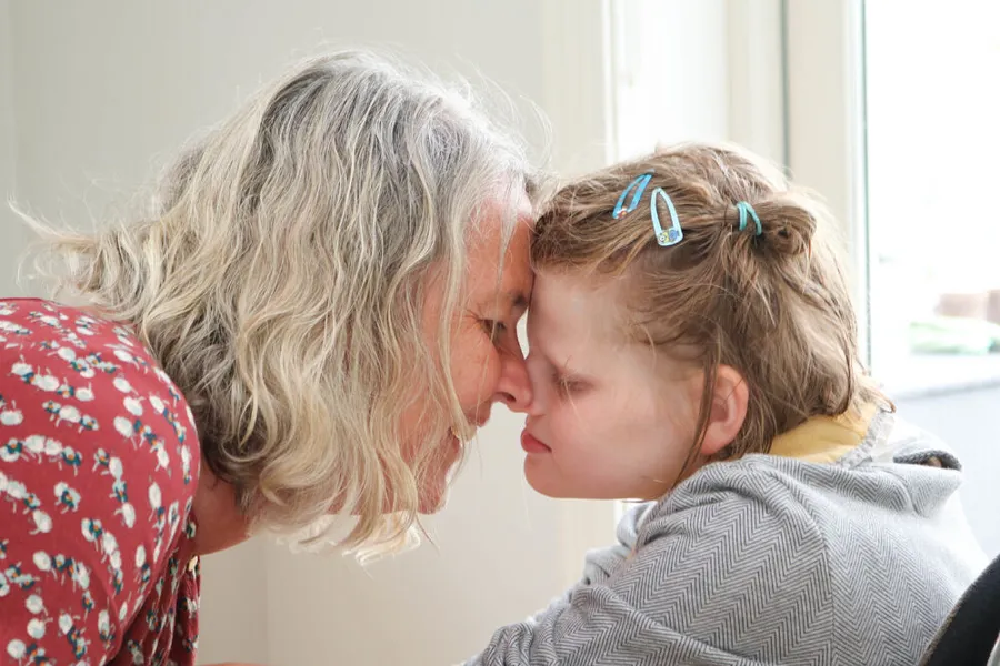 En kvinne og en en jente. Pannene deres berører hverandre.