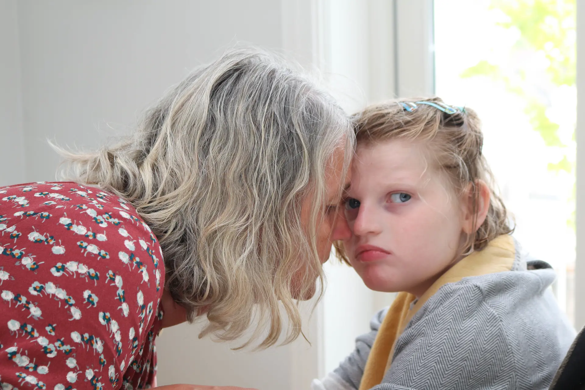 Mor og datter helt tett, panne mot panne. Datter til høyre, hun ser i kamera.