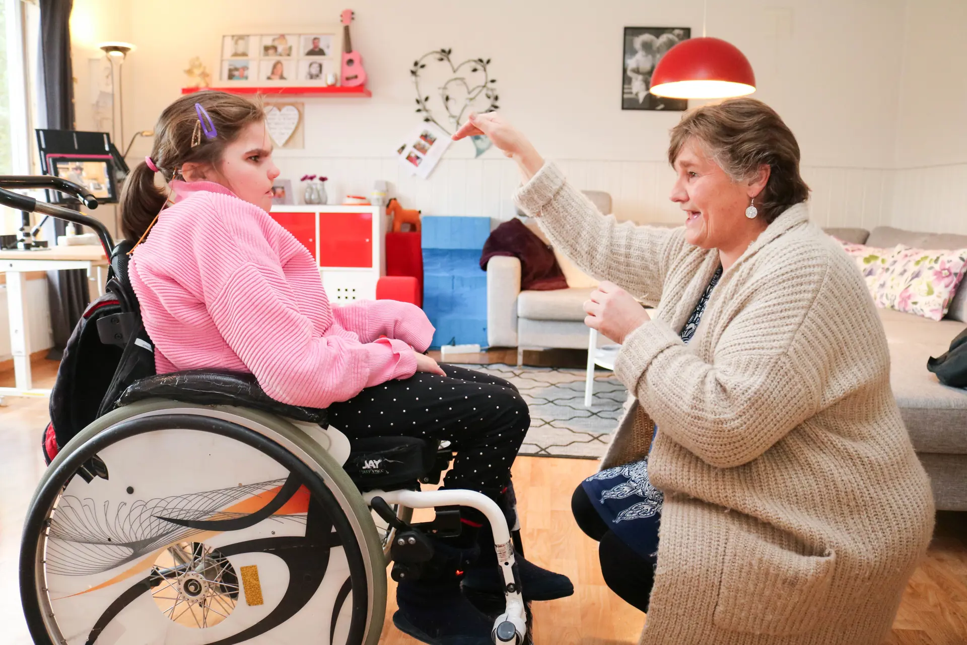 Kvinne kommuniserer ved tegnspråk sammen med sin datter, som sitter i rullestol